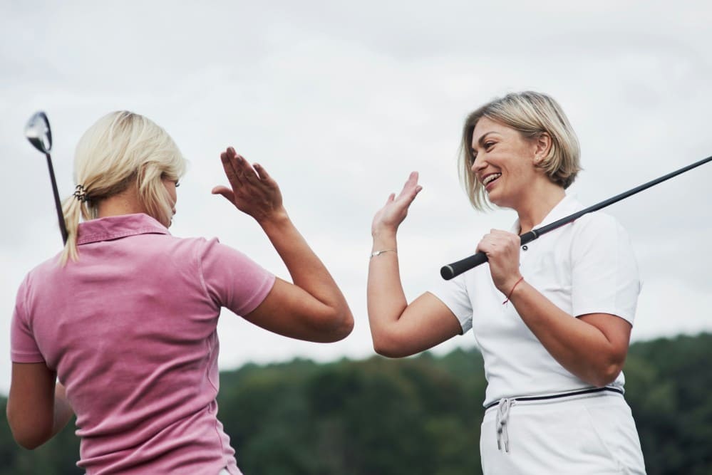 Photo de deux golfeuses en catégorie golf femme senior se tapant dans la main après avoir gagné une partie