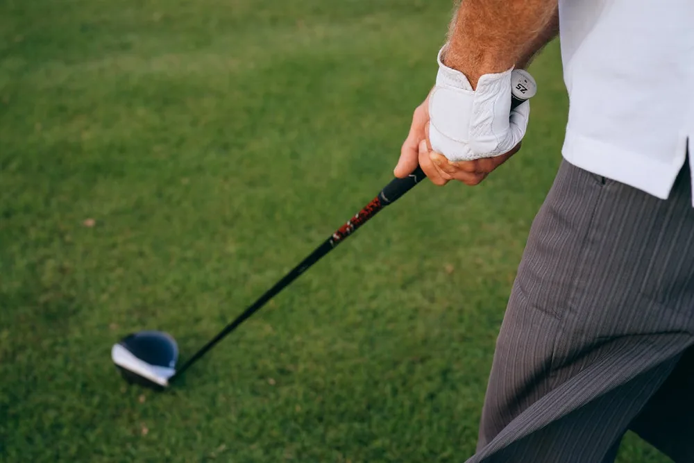 Mains tenant un club de golf avec gant, golf arthrose mains et grips adaptes