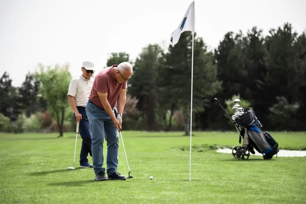Deux seniors pratiquant le putting sur green, reprise golf apres prothese arthrose