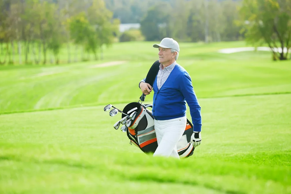 Golfeur senior marchant sur un parcours herbeux démontrant qu'arthrose et golf sont compatibles