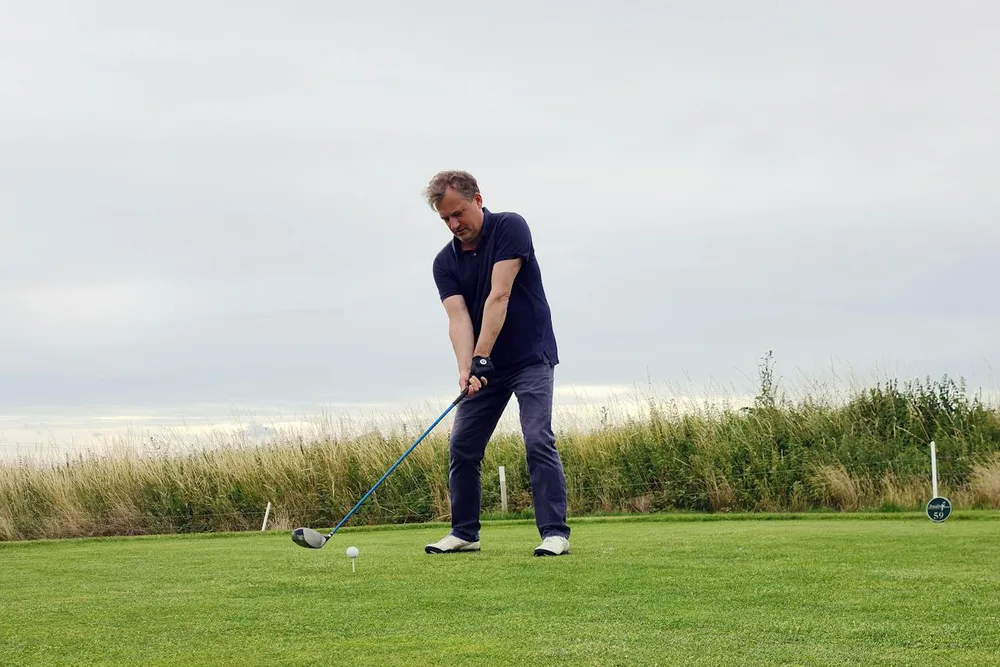 Golfeur en position d'adresse avec driver au tee-box, technique alignement coup de départ golf