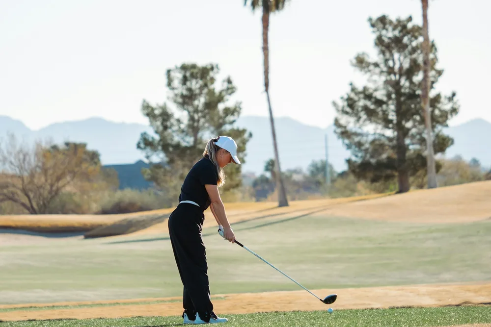 Femme golfeuse débutante avec son driver sur un parcours ensoleillé, clubs golf femme