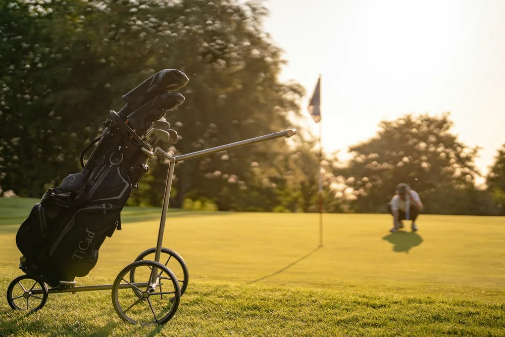 Chariot de golf sur un fairway en lumière dorée, illustration du matériel adapté pour les seniors après 70 ans