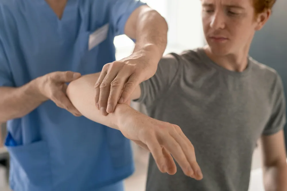 Exercice de rééducation pour le golf elbow : flexion excentrique du poignet avec haltère sur une table