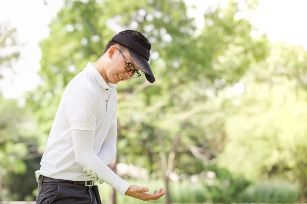 Golfeur se tenant le coude douloureux sur le parcours, symptômes caractéristiques du golf elbow
