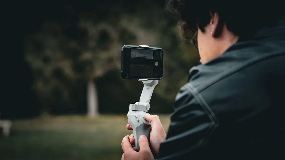 Un homme filme un swing golf ralenti en extérieur avec un téléphone monté sur un stabilisateur.